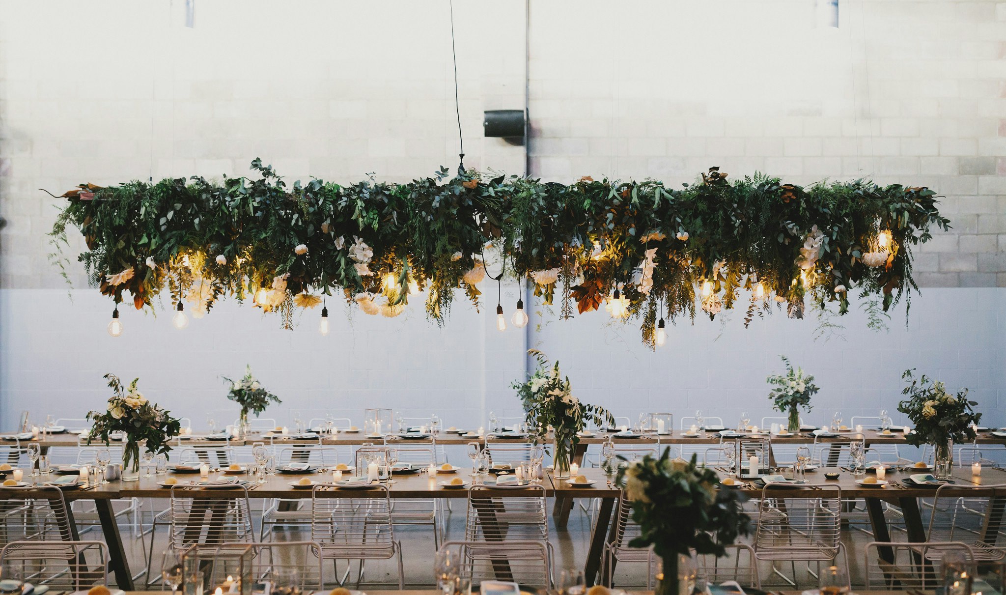 Large overhead floral installation above wedding reception tables.